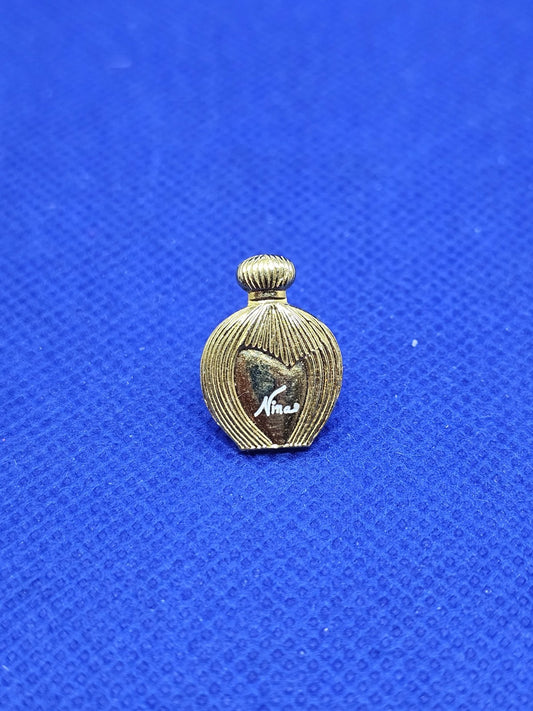 Pin’s Nina Nina Ricci parfum vintage métal doré années 900